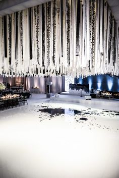 a large room filled with lots of black and white curtains hanging from the ceiling over tables