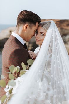 a bride and groom standing next to each other under a veil on their wedding day