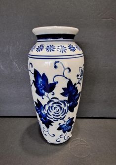 a blue and white vase sitting on top of a gray floor next to a wall