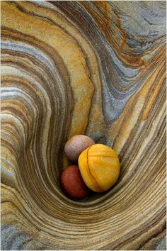 two rocks sitting in the middle of a swirly rock formation with yellow and brown colors