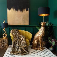 a living room with green walls and gold cat statue on the floor next to a yellow chair