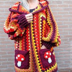 a woman wearing a colorful crocheted jacket with mushrooms on the front and sides