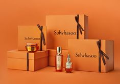 an assortment of skin care products displayed in orange boxes with black ribbon on top and the words sulhwasoo written across them