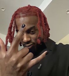 a man with red dreadlocks making a funny face while holding his finger up