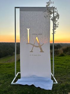 a white banner with the letter l on it in front of a field at sunset