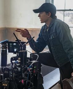 a man is standing in front of a camera with his hand on the tripod