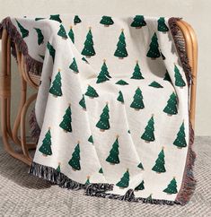 a white blanket with green christmas trees on it