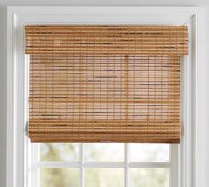 a bamboo blind in front of a window with the blinds pulled back to allow natural light