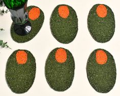 four green and orange coasters sitting on top of a white table next to a vase