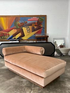 a large tan couch sitting in front of a painting on the wall next to a chair