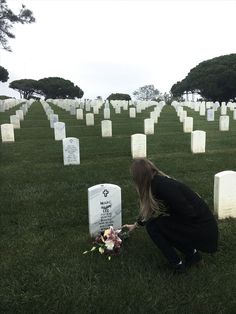 a woman kneeling down next to a grave