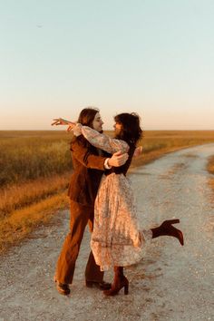 a man and woman kissing on the side of a dirt road