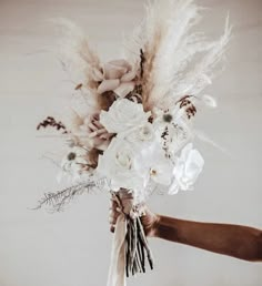 a person holding a bouquet with flowers and feathers