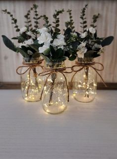 three mason jars filled with flowers and lights