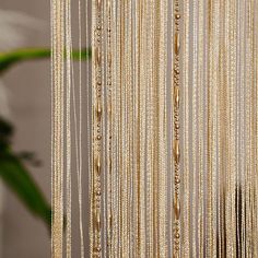 beads hanging from the side of a wall next to a vase with a plant in it