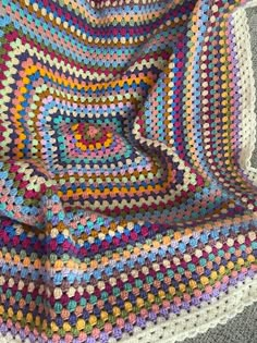 a multicolored crocheted blanket on the floor