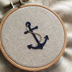 an embroidered anchor on a piece of fabric with a wooden hoop hanging from the side