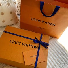 two louis vuitton bags on a bed with blue ribbon and tags attached to them