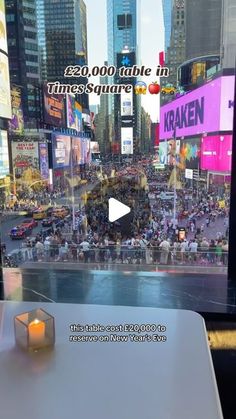 a table with a candle on it in front of a large city street filled with people