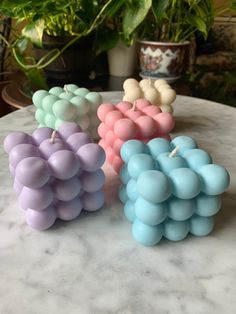 three small candles sitting on top of a marble table next to a potted plant