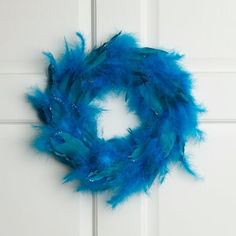 a blue feather wreath hanging on a white door