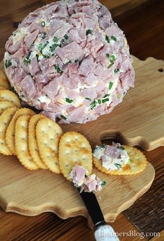 a platter with crackers and cheese on it next to a bowl of meat