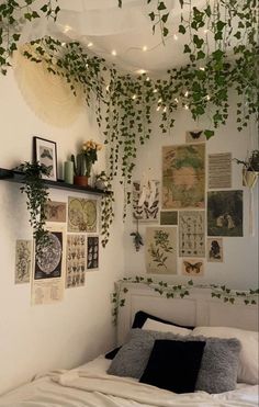 an unmade bed with lots of plants hanging from the ceiling and pictures on the wall