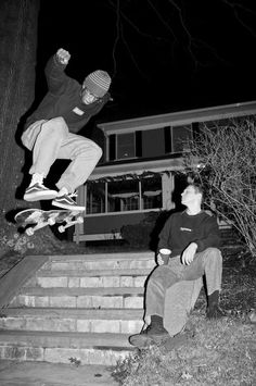 a man flying through the air while riding a skateboard next to another man sitting down