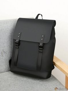 a black leather backpack sitting on top of a gray couch next to a wooden bench