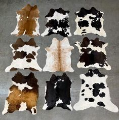 six different colored and black and white cowhides laid out on the cement floor