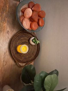 two bowls with eggs and some vegetables on a table next to a potted plant