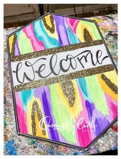 the welcome sign is painted with gold glitters and has a name that reads,'welcome'on it