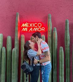 a man and woman kissing in front of a neon sign that says mexico mi amo