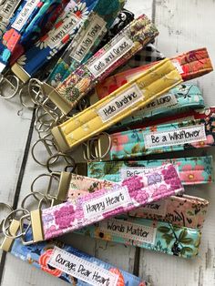 the keychains are all different colors and have sayings on them, along with flowers