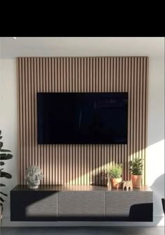 a flat screen tv mounted to the side of a wall in front of a potted plant