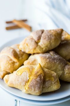 several pieces of bread on a plate with cinnamon sticks in the background and text overlay that reads, sopapilla cheesecake rolls