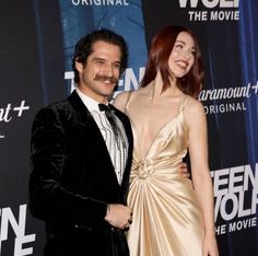 a man and woman standing next to each other on a red carpet at an event