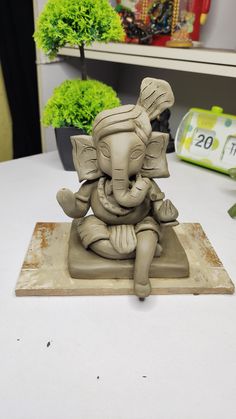 an elephant statue sitting on top of a white table next to a potted plant