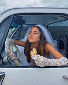 a woman sitting in the driver's seat of a car holding a piece of fruit