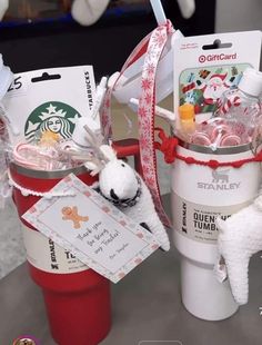 two starbucks coffee cups with christmas decorations on them and some candy wrapped in red ribbon