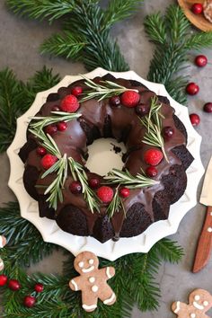 a chocolate cake with icing and christmas greenery on top, surrounded by cookies