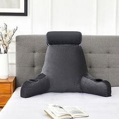 an inflatable pillow sitting on top of a bed next to a book and vase