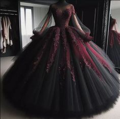 a black and red ball gown with long sleeves on display in front of a mirror