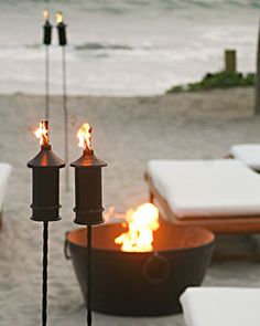 two torches are lit on the beach near chairs