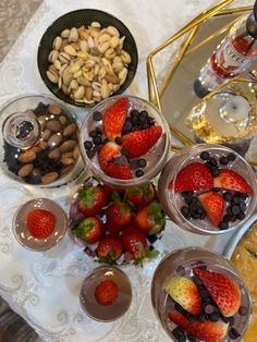 four desserts are arranged on a table with nuts and strawberries in bowls, one is filled with chocolate