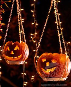 three pumpkin shaped lanterns hanging from chains with lights on the sides and two jack - o'- lantern faces carved into them