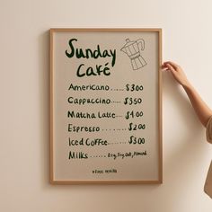 a woman is pointing to a poster on the wall that says sunday cake with coffee