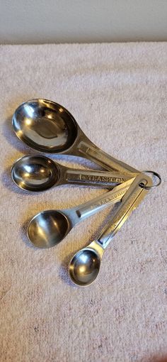 three metal measuring spoons sitting on top of a white towel