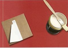 a can of paint and a knife on a red tablecloth with a white tag