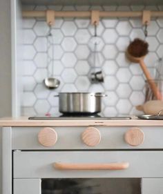 a stove top oven sitting inside of a kitchen next to a wooden spoon and pan